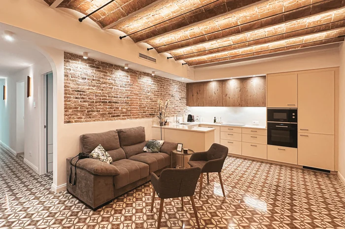 Salón y cocina reformados en La Nova Esquerra, con bóvedas, ladrillo visto y pavimento geométrico